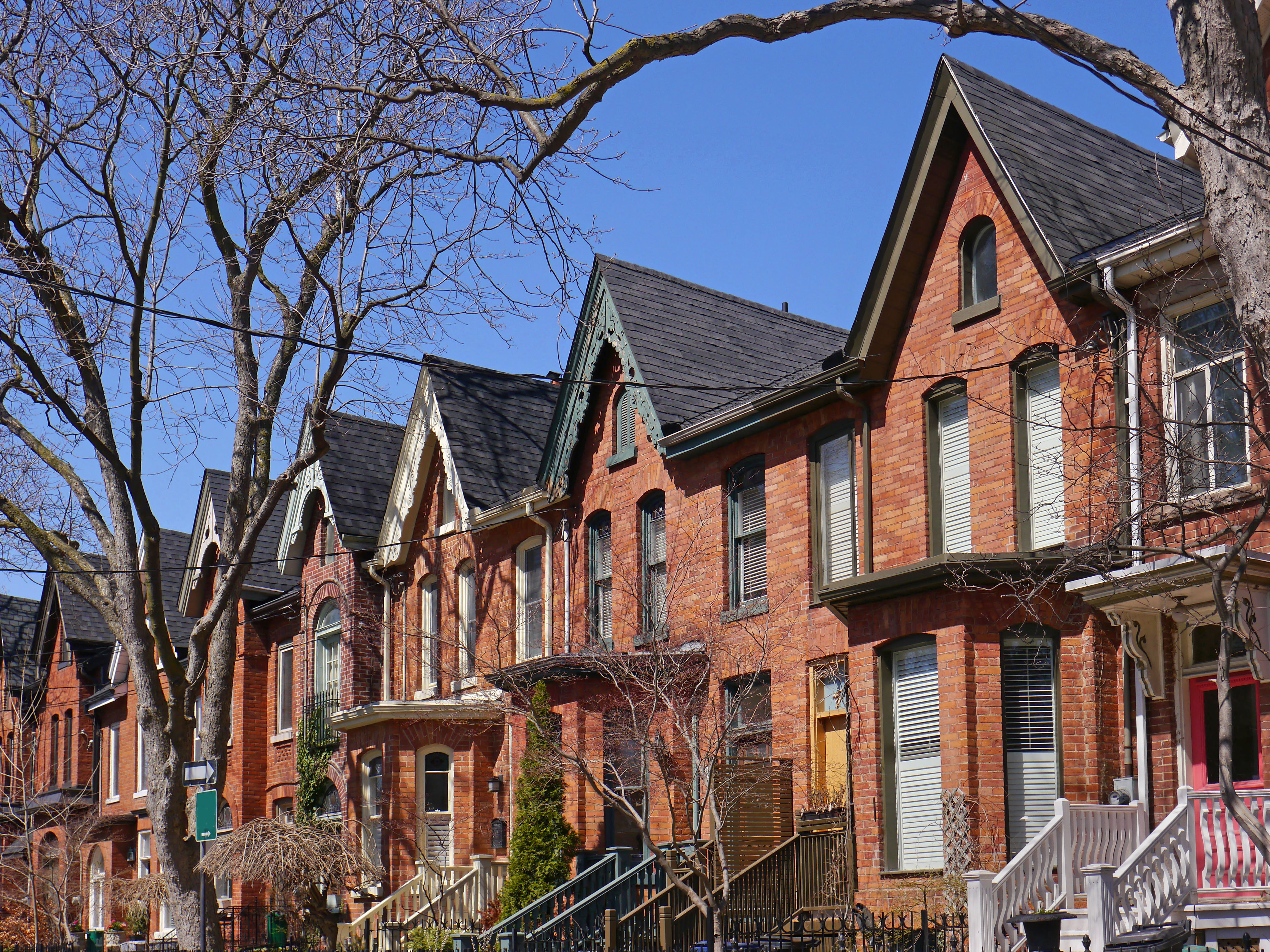 Row of semi-detached Bay-and-Gable red-brick houses with trees in the foreground